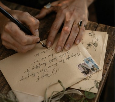 A hand addressing an envelope in ink